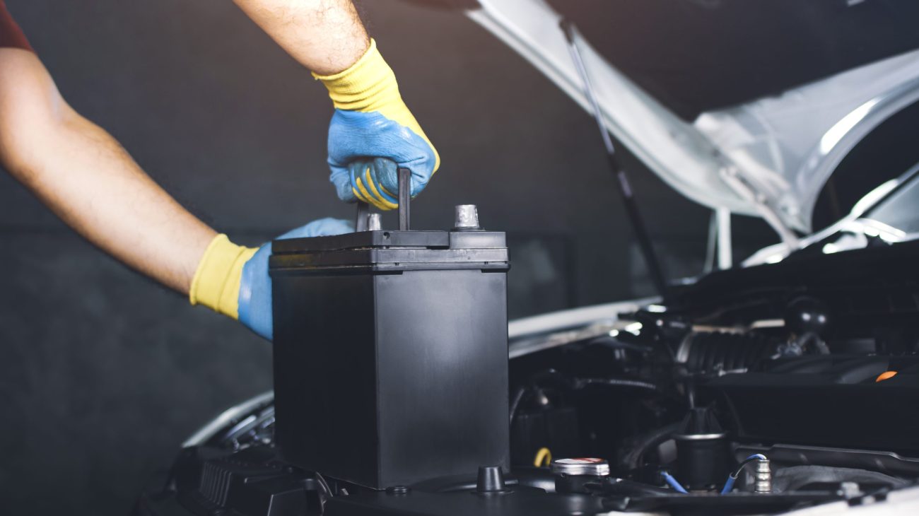 The Mechanic hand is pulling up an car old battery for replacement